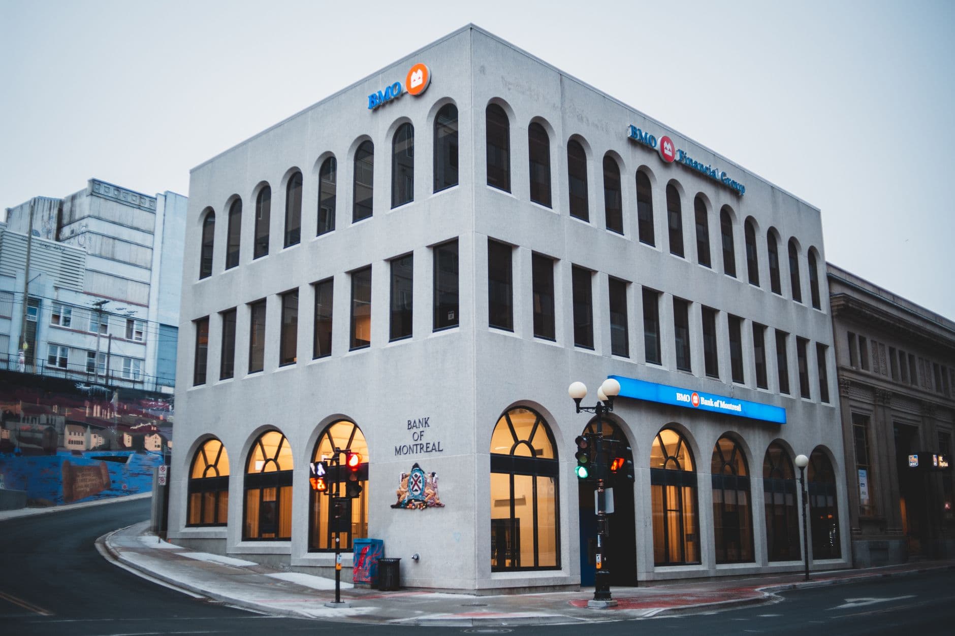 Exterior of contemporary building of bank with arched passages near asphalt road in evening